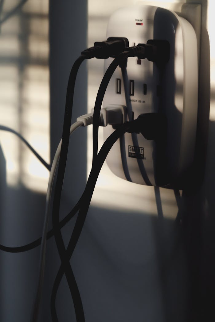 Multiple charging cables plugged into a wall outlet, showcasing energy connectivity.